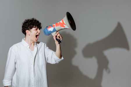 curly haired man shouting through megaphone