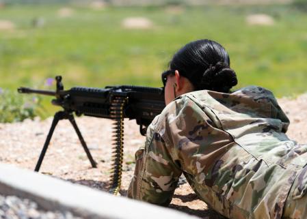 woman lying on ground aiming a firearm