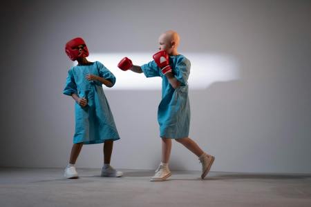 child wearing a hospital gown and boxing gloves